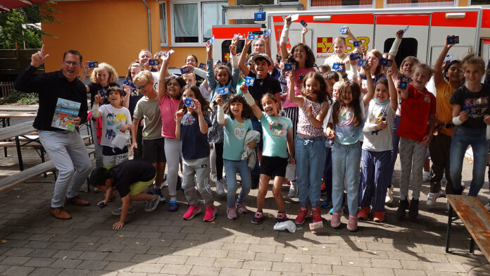 Kinder aus dem Sommercamp jubeln vor einem ASB Rettungswagen